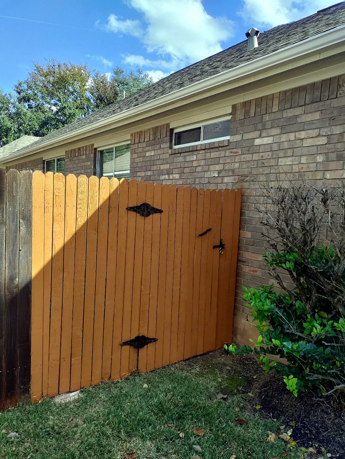 Side view of completed wood fence repair and staining in the Austin area.